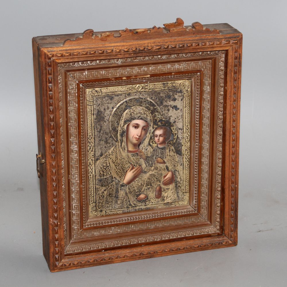 A late 19th century Russian tempera on panel icon, with silver gilt oklad dated 1889, housed in an ornate carved wood casement frame,
